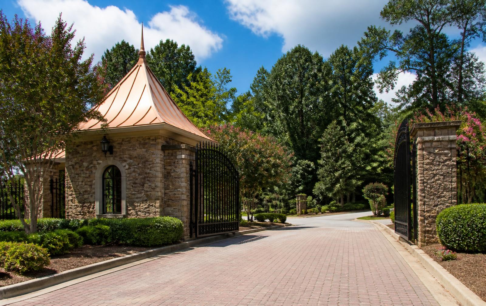 Stone gatehouse and open wrought-iron gates at the entrance to a gated Charlotte-area community