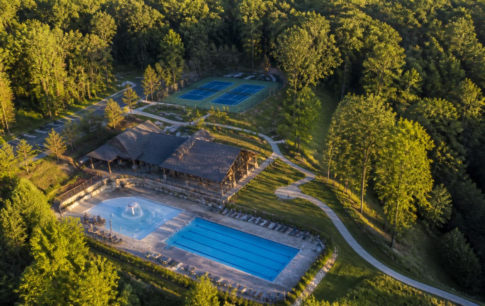 Overhead view of the Camp Sanctuary amenity campus — pool, timber lodge, courts, and forested paths inside the community
