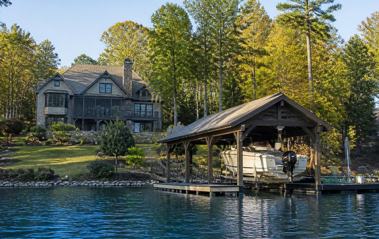 Lakefront shingle-style home with a covered private dock and boat lift seen from the water